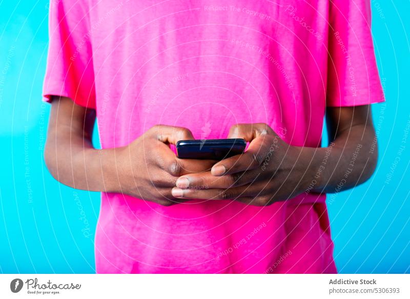 Anonymous black man using smartphone male young african american ethnic casual bright colorful browsing surfing device mobile wireless connection cellphone