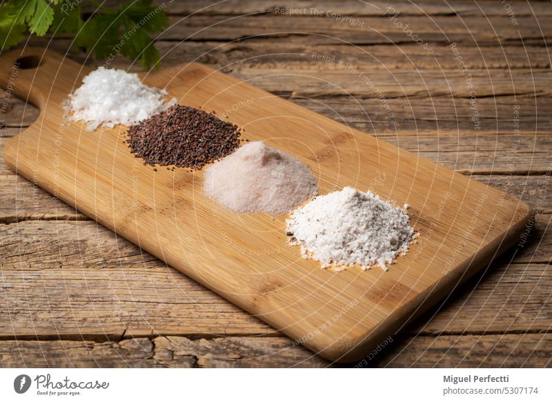 Wooden table with lots of different types of salt, black, pink, flakes and seasoned with truffles, on a rustic wooden background. condiment assortment various
