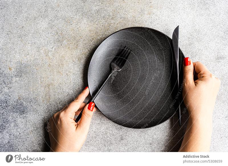Minimalistic table setting on concrete background black cutlery dark diet dinner eat eating fasting hand meal minimal minimalism minimalistic place plate red