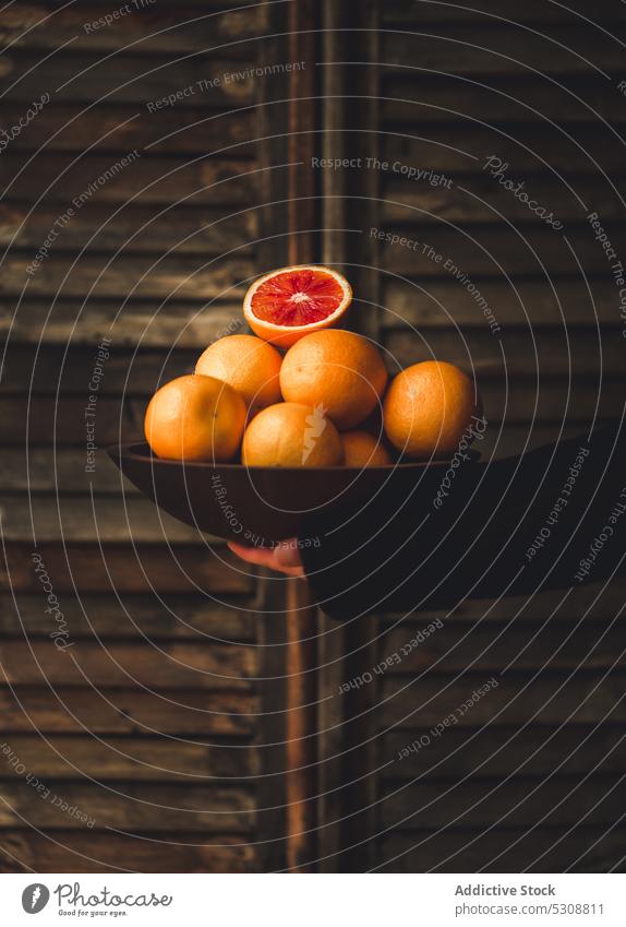 Ripe red oranges in black bowl against wooden wall person ripe juice fruit citrus fresh food sweet healthy vitamin delicious organic tasty natural nutrition