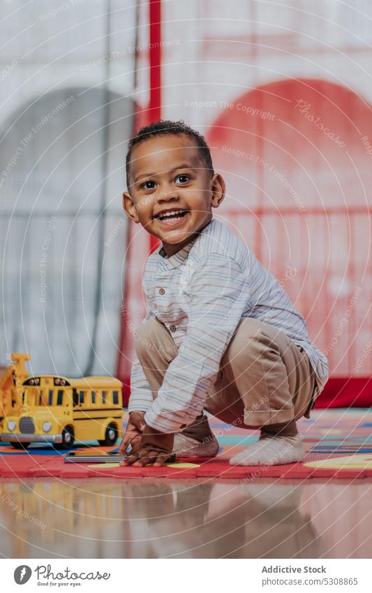 Smiling cute little boy playing with toys toddler relax carpet colorful smile at home glad delight adorable happy child black african american ethnic kid