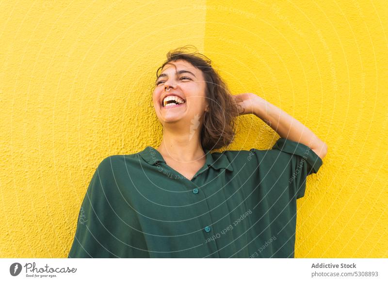 Smiling woman standing against yellow wall style curly hair smile cheerful bright delight colorful short hair shirt female young laugh appearance individuality