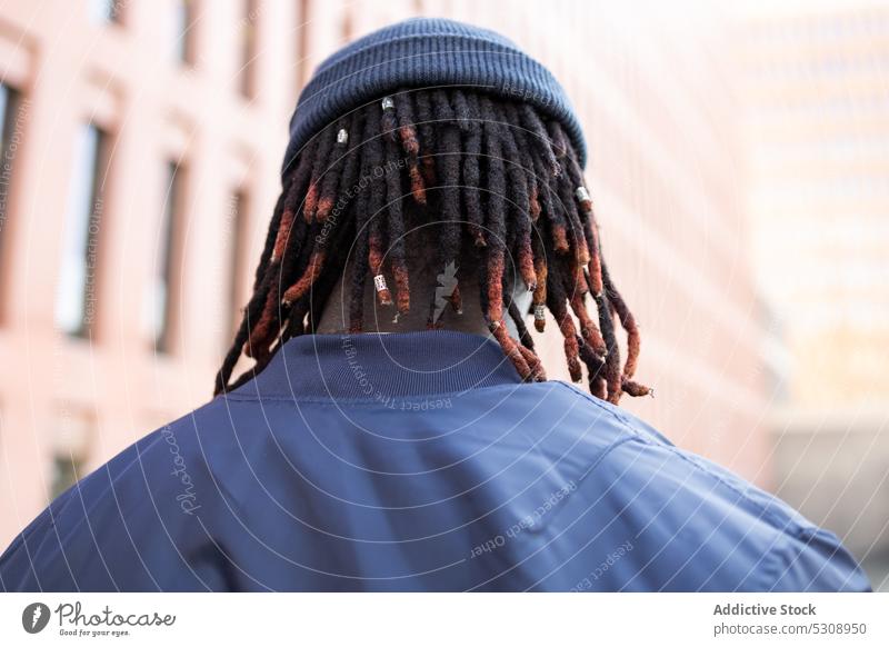 Anonymous black man with dreadlocks street braid urban style hairstyle dark hair hipster hairdo trendy hat african american town male ethnic guy outfit informal