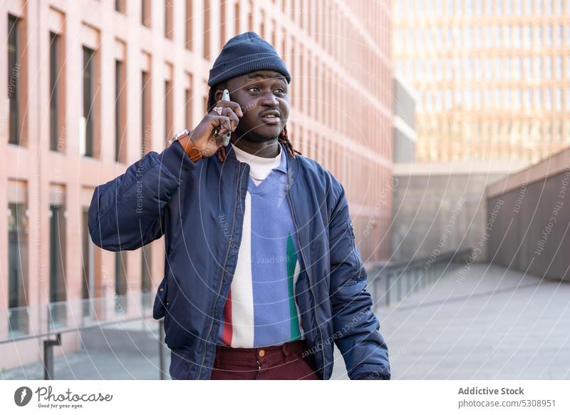 Black man speaking on smartphone talk conversation call communicate discuss street style african american male trendy outfit connection black phone call urban