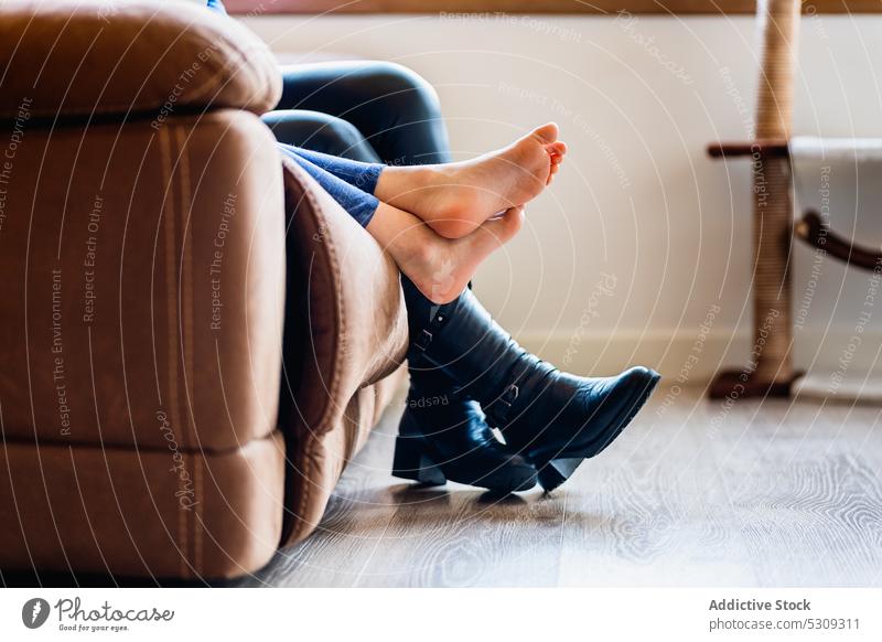 Legs of anonymous people sitting on sofa leg barefoot rest feet relax chill living room boot couch comfort leather lounge home together shoe weekend house