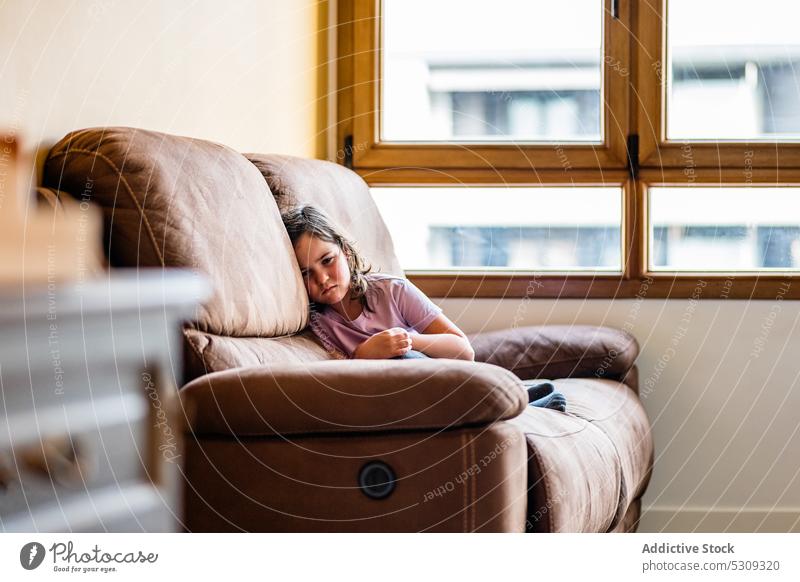 Sad girl resting on leather sofa upset child comfort home kid living room little cozy sad childhood unhappy problem frustrate sit couch adorable cute domestic