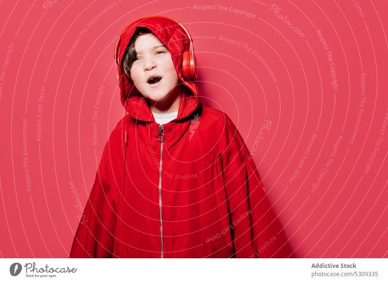 Stylish young girl in red hooded pullover with headphones listen music style trendy casual confident modern child sound sing kid bright color loud song