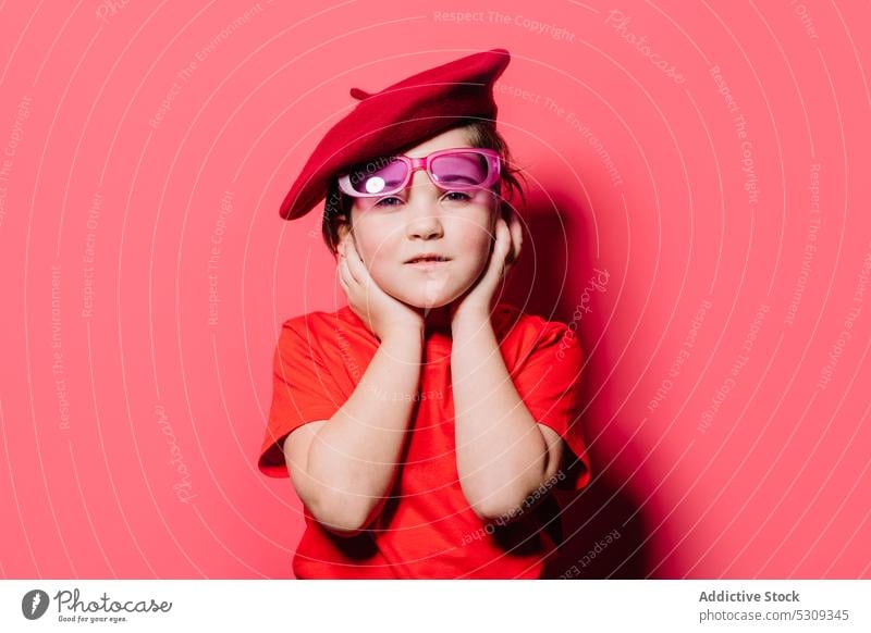 Cute little girl in red casual cloth with glasses and beret posing in studio sad style kid trendy fashion sunglasses outfit child model portrait unhappy
