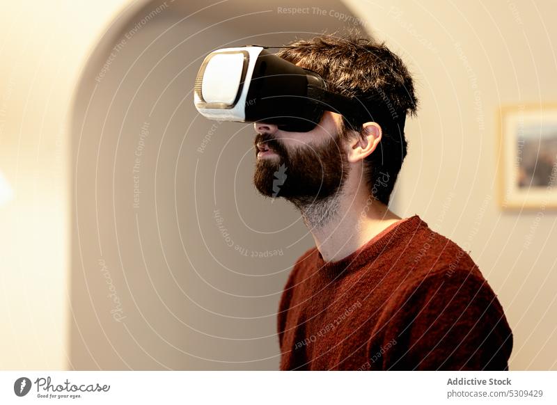 Amazed man wearing VR goggles against wall virtual reality using technology experience entertain headset gadget device gamer vr male innovation simulate digital