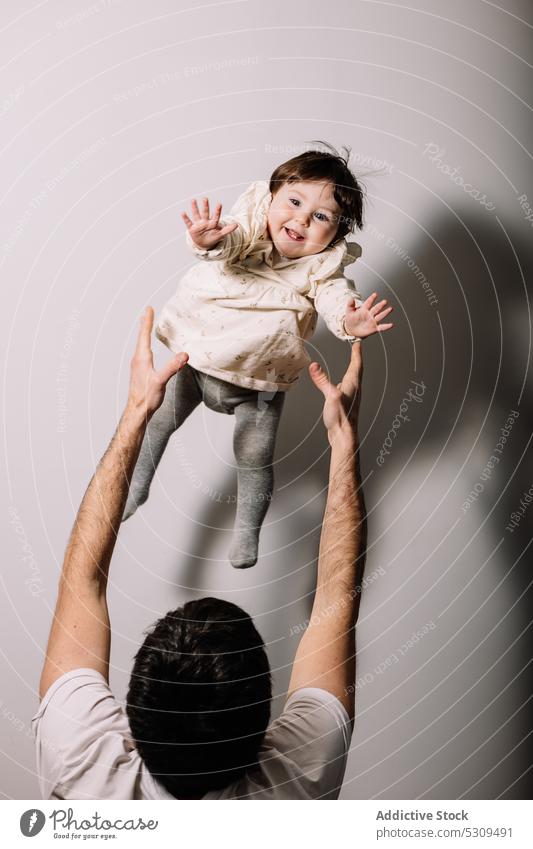 Unrecognizable man rising cute little girl on hands father child daughter raise parenthood adorable love childhood kid together positive happy male charming