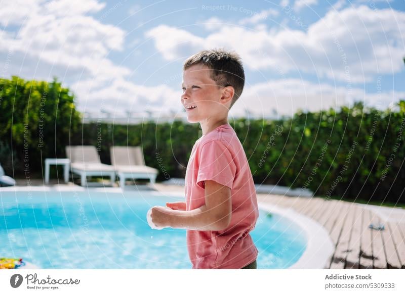 Cute boy in wet clothes near pool looking away summer poolside resort holiday vacation child kid smile rest water childhood adorable cute swim weekend sun glad