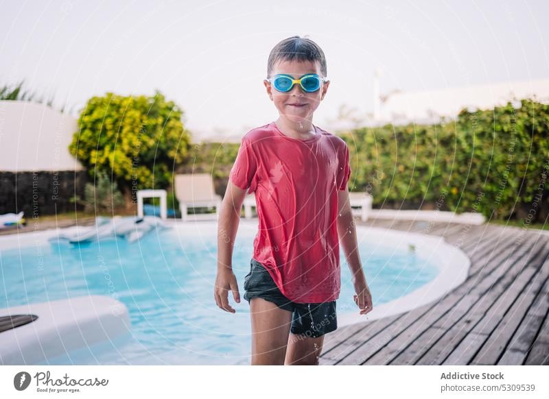 Cheerful boy in swimming goggles on poolside summer child vacation resort smile holiday kid water happy cheerful recreation positive joy wet hair pleasure
