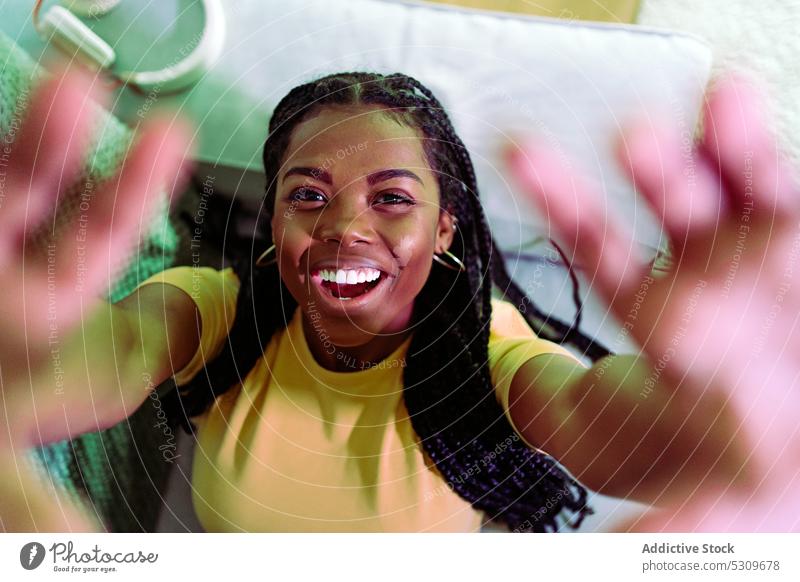 Cheerful black woman reaching hands to camera and smiling positive reach out smile couch lying cheerful braid happy carefree relax african american female young