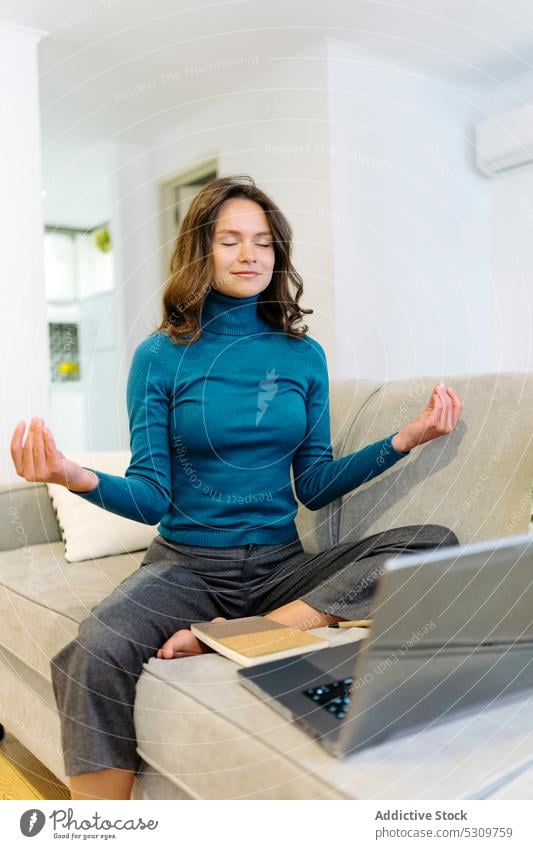 Calm woman meditating on sofa during break from work freelance laptop relax meditate remote home young online eyes closed female casual internet telework calm