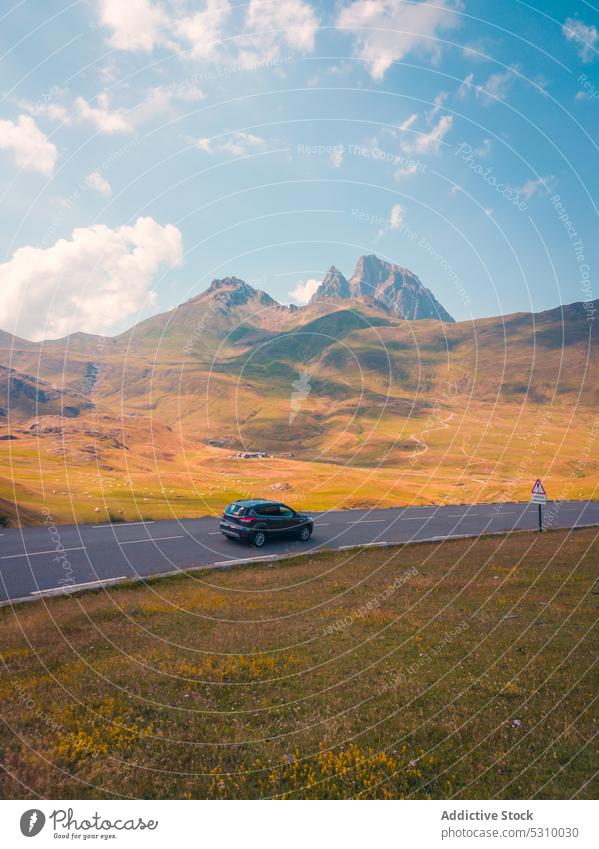 Car driving on asphalt road among mountains car nature field countryside drive blue sky cloudy vehicle anayet pyrenees huesca spain landscape grassy daytime