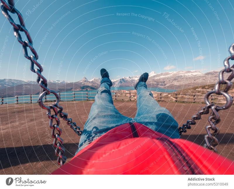Crop man on metal chain on paddock traveler swing style vacation person tourism blue sky lying mountain recreation casual relax tourist nature holiday