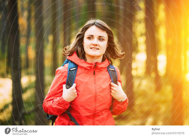 Portrait Of Active Young Adult Beautiful Caucasian Girl Woman Dressed In Red Jacket hiking In Autumn Forest. Active Lifestyle In Nature active adult authentic