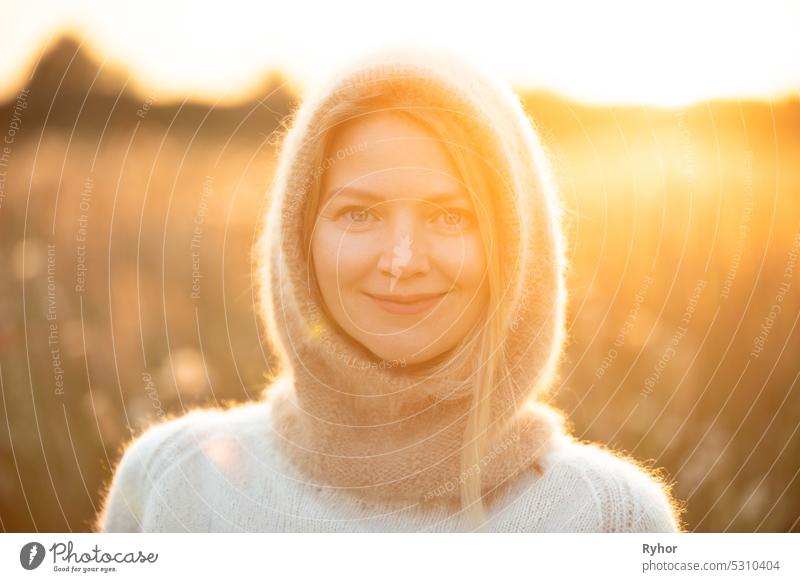 Portrait Of Young Pretty Caucasian Happy Girl Woman In Woolen Jacket Blouse And Brown knitted bonnet Posing In Early Spring Forest In Sunny Day. Enjoy Outdoor Nature. beautiful young woman smiling. power of women. knitted wear, knitted bonnet, knitwear