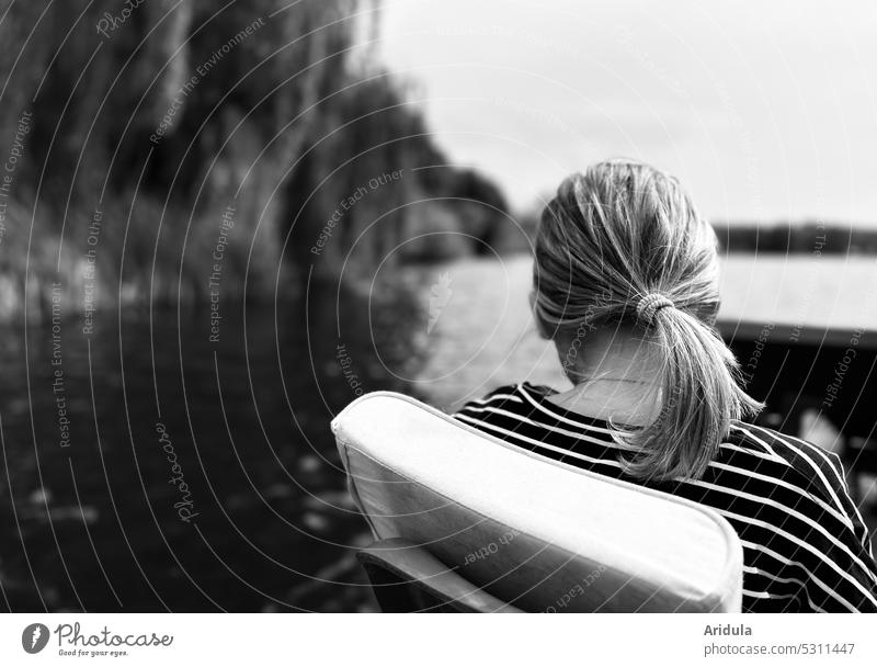 back view | girl sitting in pedal boat on lake with shore b/w Girl Lake Pedalo Child Water bank Ponytail Head hairstyle striped shirt Leisure and hobbies Trip