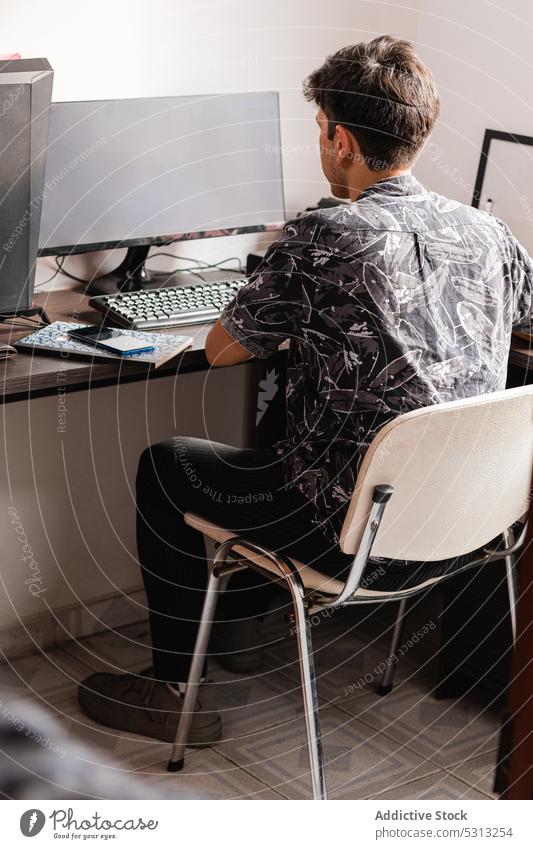 Man working on computer in home office man freelance workspace workplace telework smartphone using device job internet desk chair browsing gadget male
