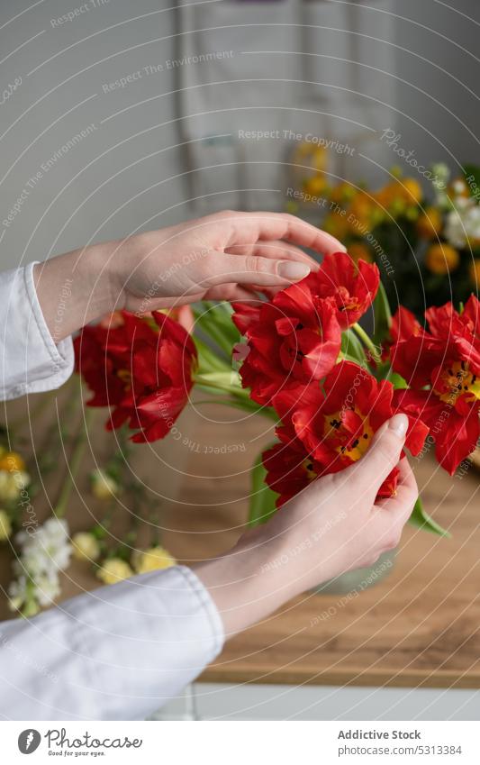 Crop woman with red flowers florist bunch bouquet work floral fresh blossom bloom female floristry store workplace shop professional job fragrant plant decor