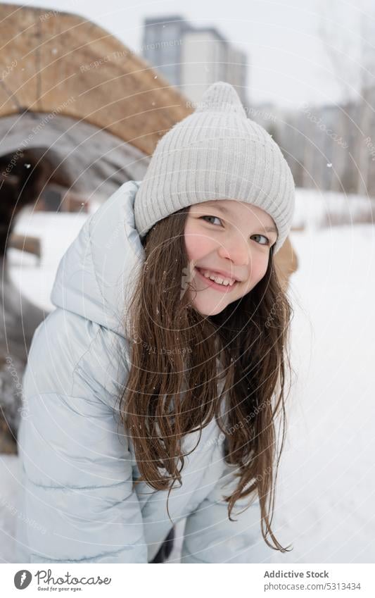 Smiling preteen girl in winter clothes standing in snow park smile warm clothes cheerful city positive happy cold glad joy outerwear optimist delight street kid