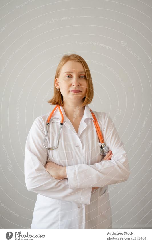 Cheerful woman standing with stethoscope in studio doctor uniform listen professional medic specialist physician female medical medicine clinic robe young