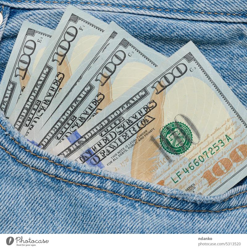 Paper American dollar bills protrude from the back pocket of blue jeans banknote business cash closeup currency denim finance financial hundred income money