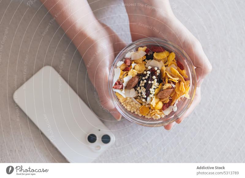 Crop person with healthy snack bowl muesli smartphone container nut breakfast seed granola lunch box vitamin food healthy food natural nutrition fresh morning