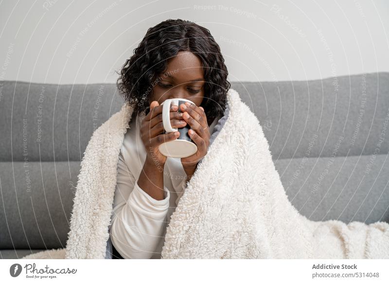 Content black woman drinking hot coffee on sofa calm hot drink comfort home cozy beverage plaid cup female couch african american young weekend tranquil mug