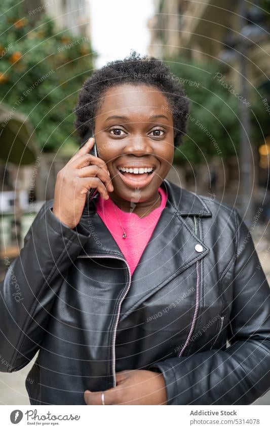 Cheerful black woman talking on smartphone phone call street speak conversation positive smile young female african american happy ethnic cheerful device