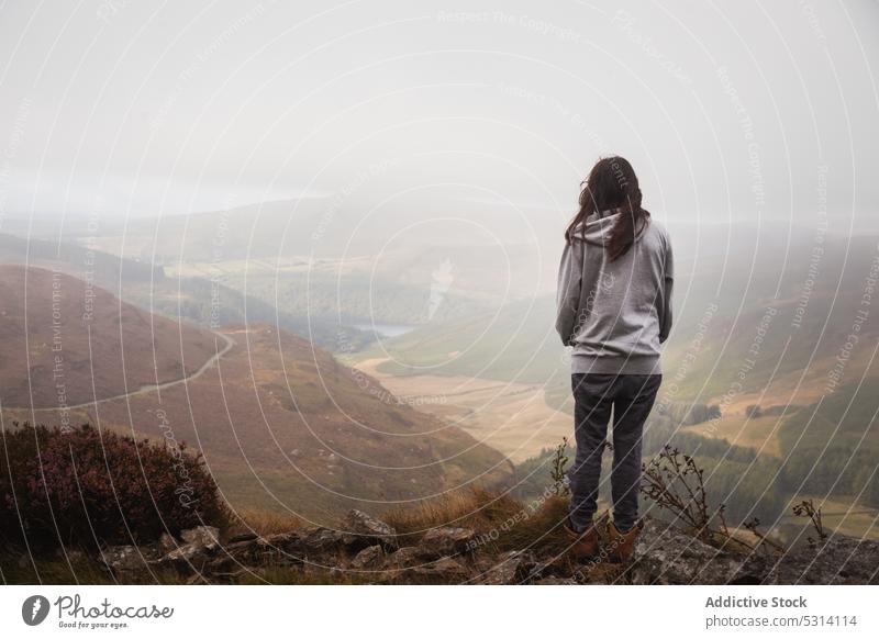 Woman standing on top of mountain and admiring view of ground woman traveler valley admire hill nature lake environment field observe ireland landscape