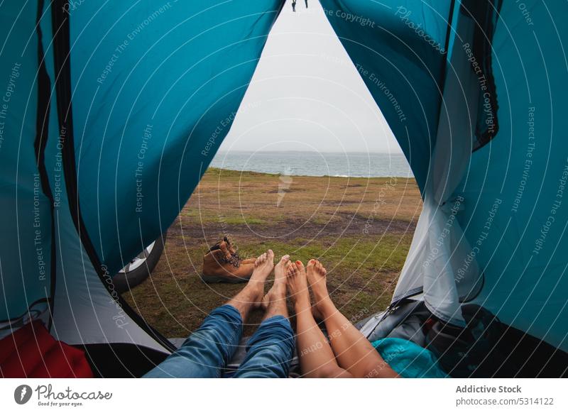 Unrecognizable young couple lying in tent on hilltop traveler camp relax mountain journey ireland vacation road trip vehicle romantic wanderlust transport