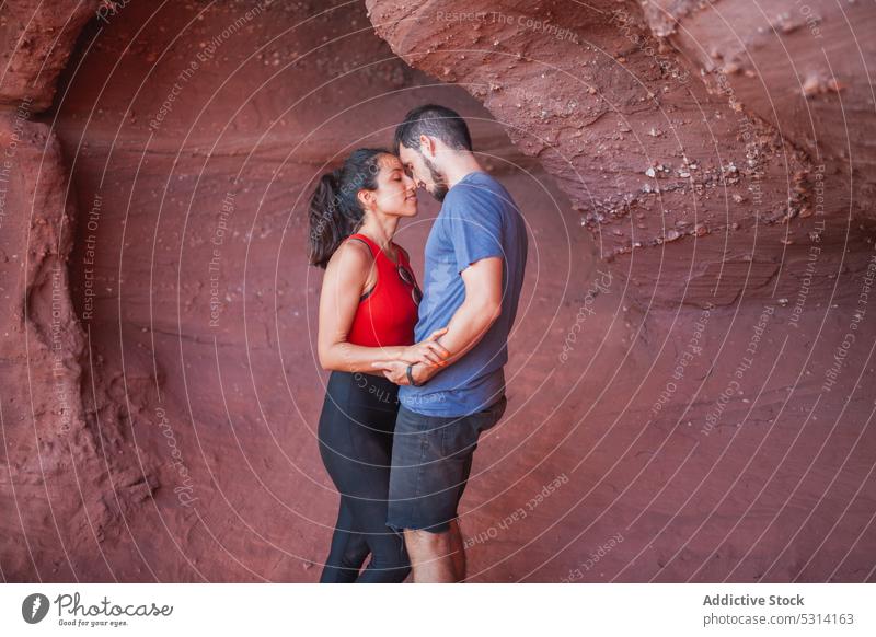 Loving couple embracing in canyon embrace cave gentle touch nose love travel vacation hug smile happy red canyon ethnic hispanic young tourist discovery harmony