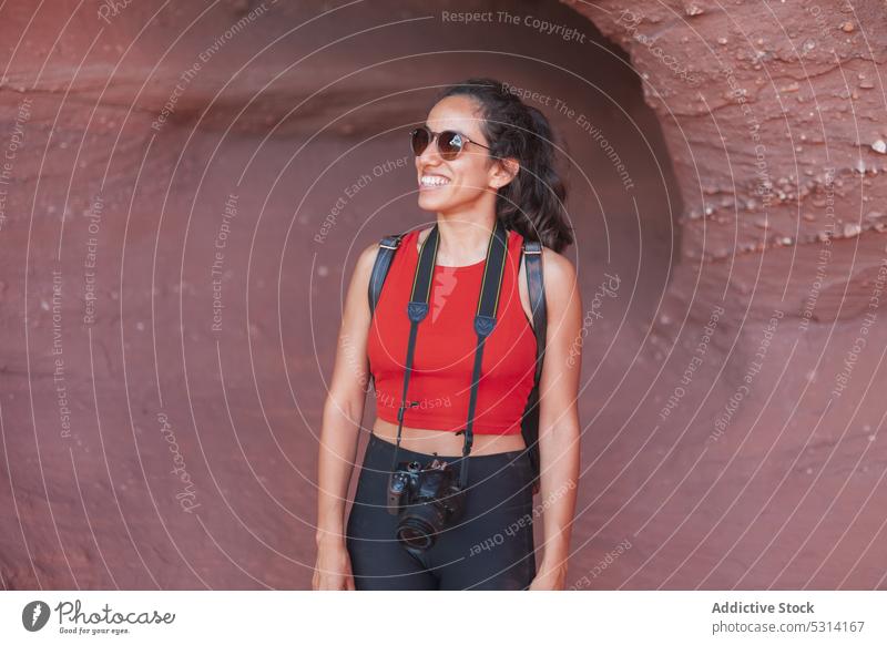 Smiling female tourist with photo camera in canyon woman photography hobby journey photographer leisure cave sightseeing smile positive young red canyon