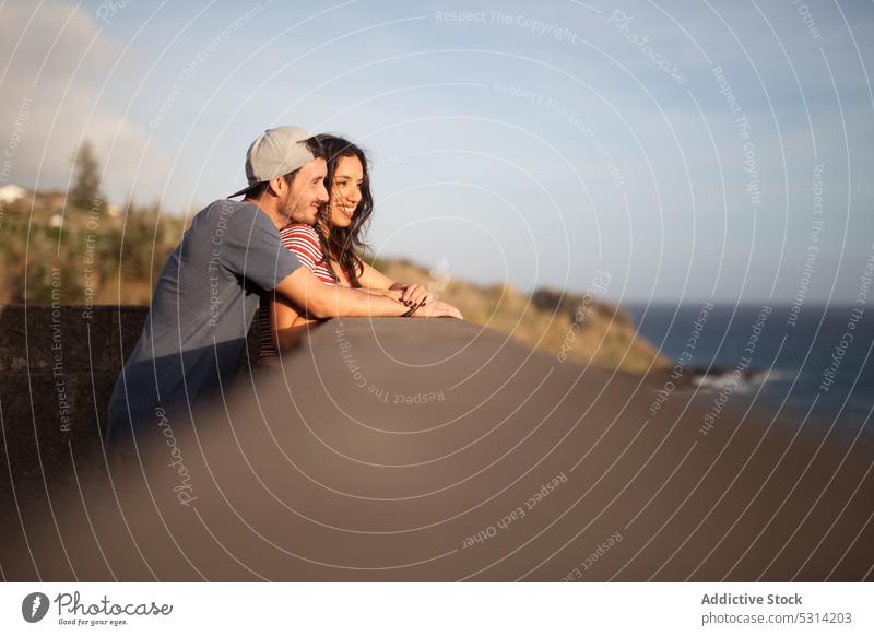 Happy couple leaning together on stone fence by sea seashore vacation embankment romantic nature seaside coast seafront portugal azores ocean relationship love