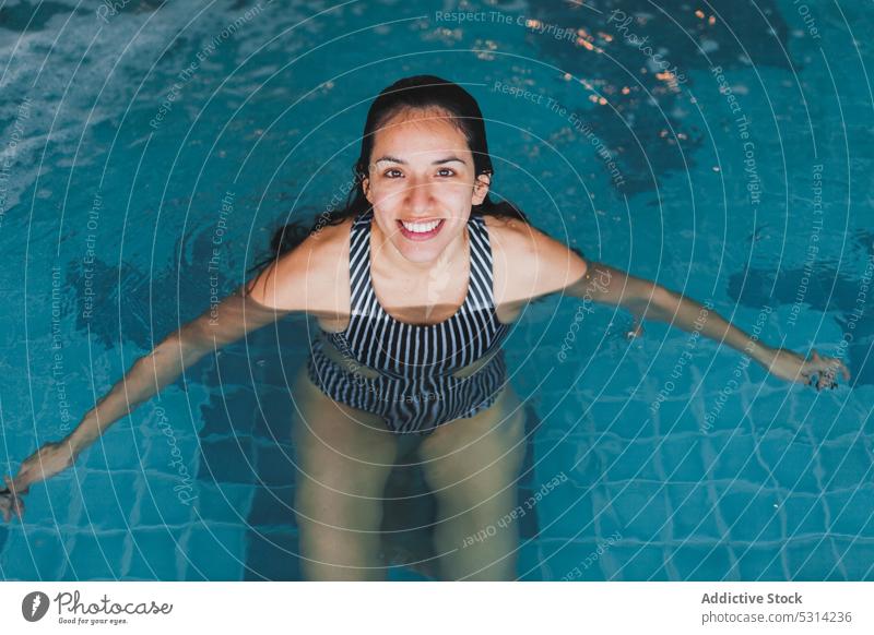 Happy swimming female in pool woman cheerful smile vacation resort happy water relax swimsuit swimwear rest stripe holiday joy lifestyle pleasure