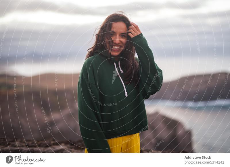 Happy woman looking at camera a cloudy day sea beach coast shore smile happy cheerful young vacation azores portugal seashore water female ocean wave nature