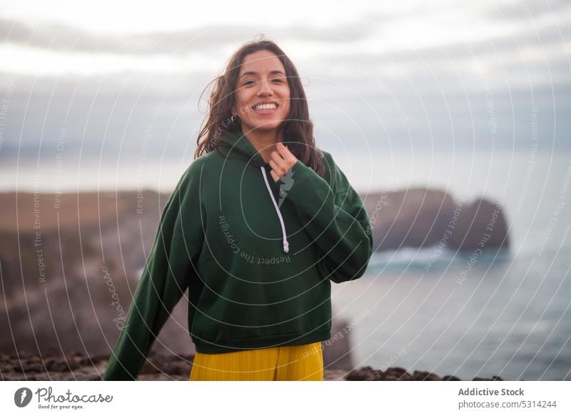 Happy woman looking at camera a cloudy day sea beach coast shore smile happy cheerful young vacation azores portugal seashore water female ocean wave nature