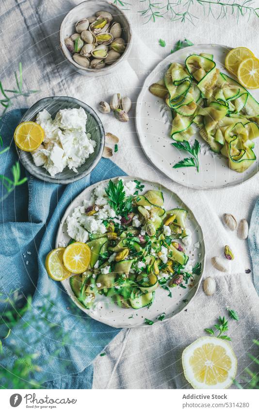 Appetizing zucchini salad with feta cheese and pistachios served on table courgette vegetable lemon dish food delicious slice healthy food gourmet appetizing