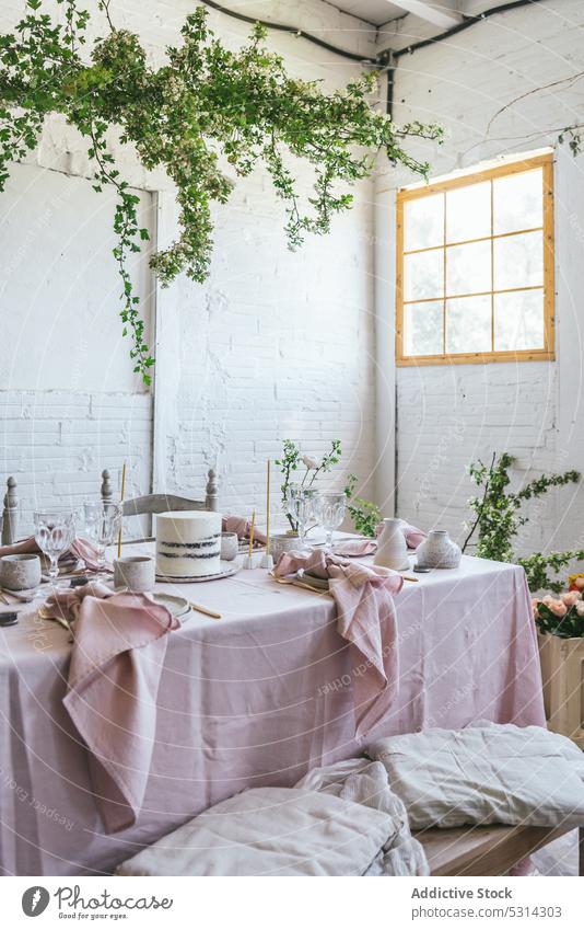 Banquet table with assorted dishware and delicious cake bench tablecloth brick wall potted plant flower creative fabric style pink cute decor interior wooden