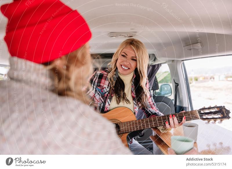 Cheerful women with guitar in car friend play guitarist cheerful together fun trip happy musician female casual young lifestyle leisure friendship practice