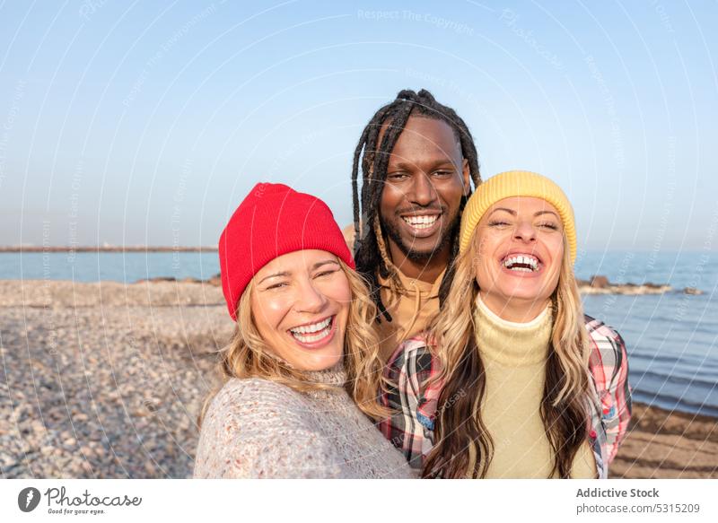 Group of happy diverse friends hugging on beach man women summer sea smile coast spend time multiracial multiethnic african american black cheerful pebble
