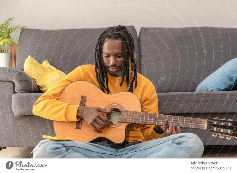 Cheerful black man playing guitar music musician living room hobby smile cheerful dreadlocks instrument home guitarist happy male sit melody talent song ethnic