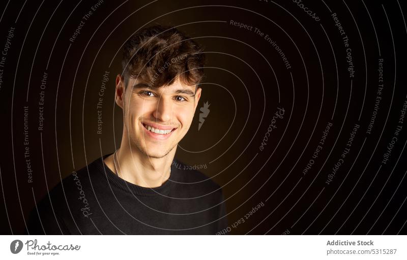 Cheerful teen boy standing against dark brown background man smile portrait style positive appearance individuality cheerful young friendly curly hair happy