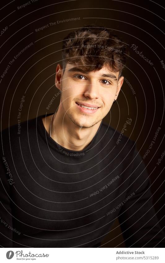 Cheerful teen boy standing against dark brown background man smile portrait style positive appearance individuality cheerful young friendly curly hair happy