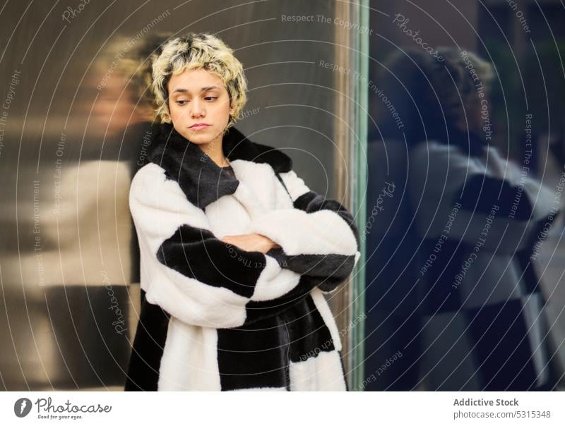 Dreamy woman in fur coat on street style lean wall fashion pensive thoughtful urban trendy female outfit building appearance dreamy short hair city calm young