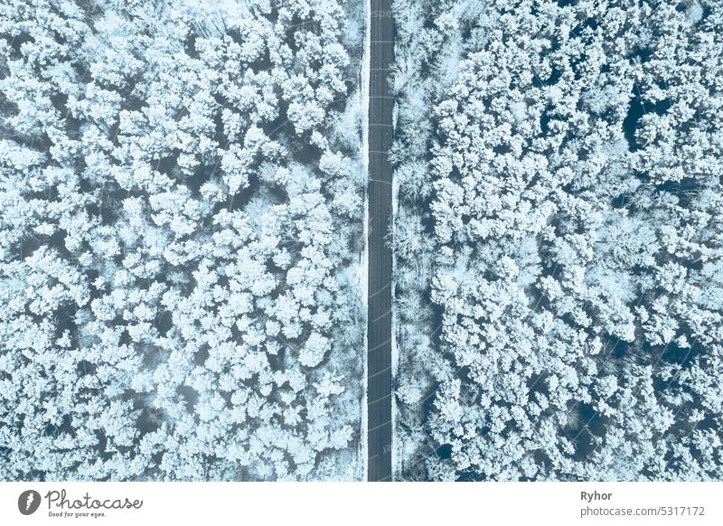 Aerial view of highway road through snow forest landscape in winter. Top view flat view of highway motorway freeway from high attitude. Trip and travel concept