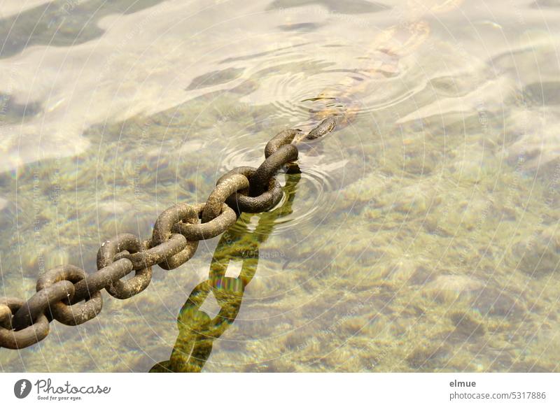 solid steel chain, lightly tensioned and partly in the water Iron chain Sling chain Boat anchoring Chain links Water Chained up Connectedness reflection Rust