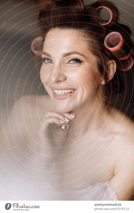 beauty concept. portrait of a beautiful young showy brunette woman with bright pin-up make-up in pink curlers. Studio Shot, Cropped. Facial treatment . Cosmetology , skin care and spa